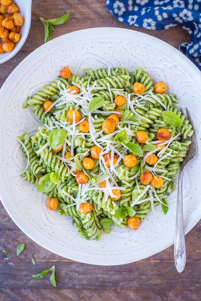 a bowl of hidden veggie pesto pasta topped with chickpeas and cheese