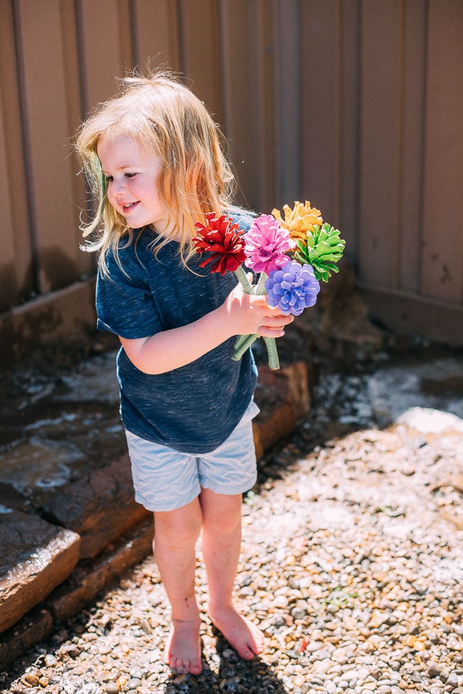 Child holding a bouquet of pinecone flowers